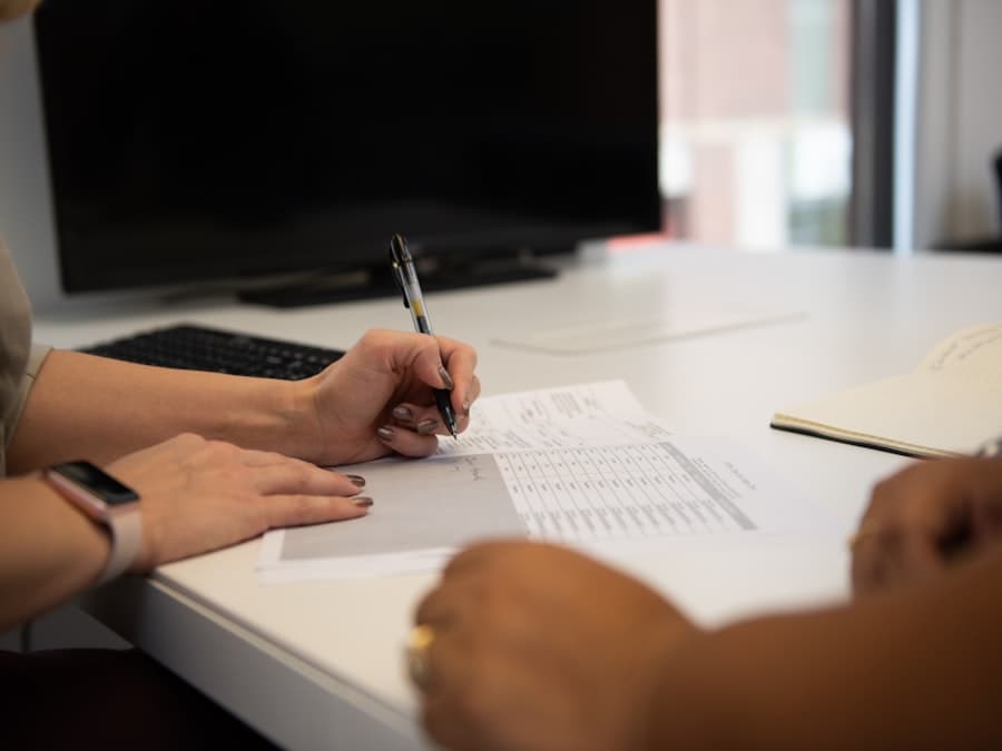 Two people working through paperwork across an office desk